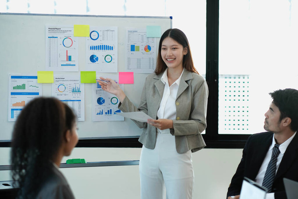 Weibliche Betriebsleiterin hält Meeting-Präsentation für ein Team von Ökonomen. Asiatin verwendet digitales Whiteboard mit Wachstumsanalyse, Diagrammen, Statistiken und Daten. Menschen arbeiten im Business Office - Foto, Bild