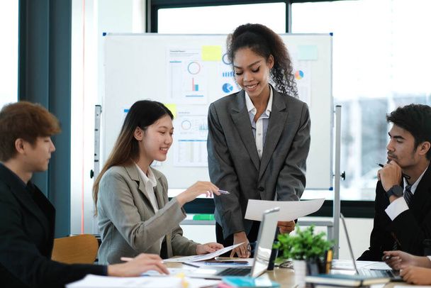 Лідер азіатської бізнес-жінки на зустрічі зі своїми багатонаціональними колегами в офісі, представляючи дані про продажі або прогнози проджек - Фото, зображення