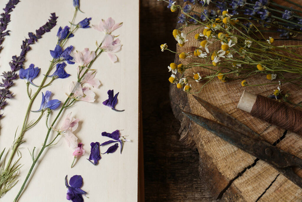 Composition with beautiful dried flowers and book on wooden table, top view - Foto, afbeelding
