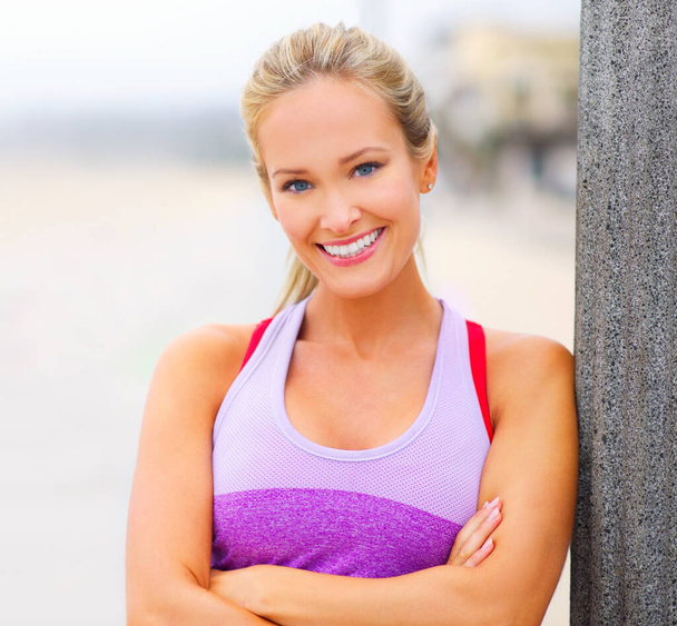 In shape and feeling great. Portrait of a young woman in sportswear standing at the beach - Foto, afbeelding