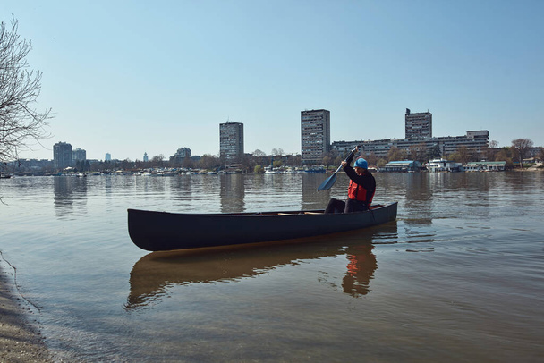 Kentsel alanda Tuna nehrinde bir kanoda kürek çeken bir adam, küçük bir eğlence kaçışı, hobiler ve açık hava sporları.. - Fotoğraf, Görsel