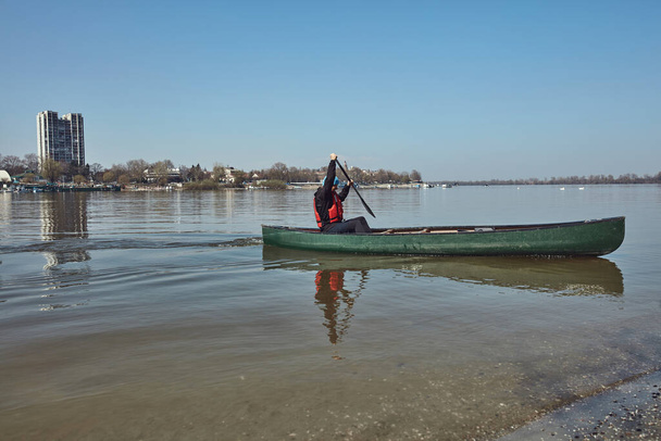Man paddling in a canoe on a Danube river in urban area, small recreational escape, hobbies and sports outdoors. - Photo, Image