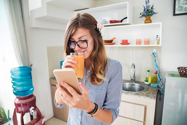 Giovane donna adulta che utilizza lo smartphone in una casa moderna. - Foto, immagini
