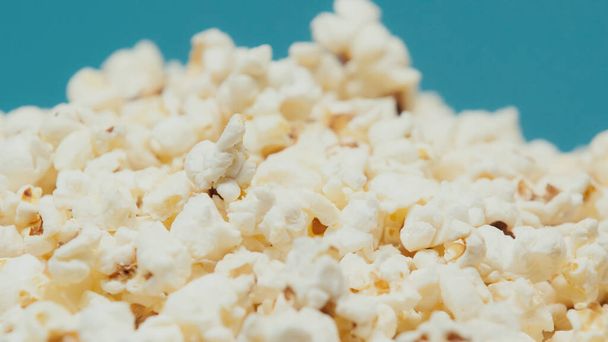 close up view of delicious and salty popcorn isolated on blue - Zdjęcie, obraz