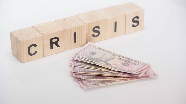 bankbiljetten in de buurt van houten kubussen met crisisbelettering op witte achtergrond - Foto, afbeelding
