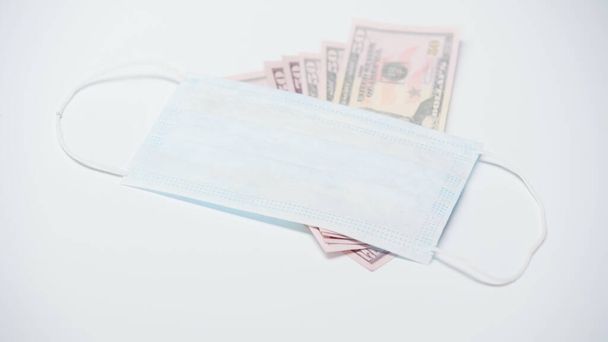 protective medical mask on dollar banknotes on white background - Fotografie, Obrázek