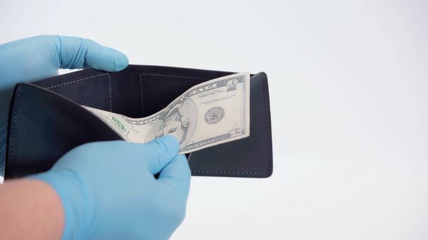cropped view of person in latex gloves holding dollar banknote and wallet on white - Foto, Bild