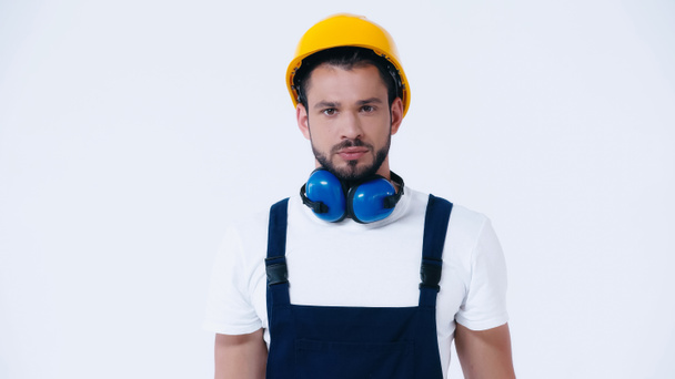 serious foreman with helmet and ear protective headphones looking at camera isolated on white - Photo, image