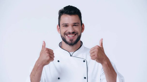 jovem chef feliz mostrando polegares para cima e olhando para a câmera isolada no branco - Foto, Imagem