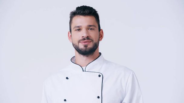 позитивный бородатый шеф-повар в форме смотрит на камеру, изолированную на белом - Фото, изображение