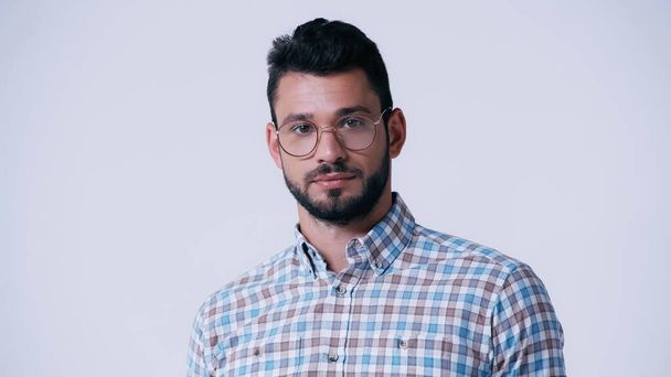 young bearded nerd in eyeglasses and plaid shirt looking at camera isolated on grey - Photo, Image