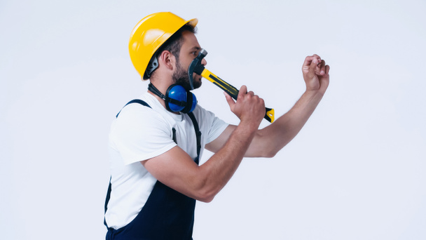 side view of handyman in hardhat working with hammer isolated on white - Foto, Bild