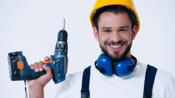 young repairman with electric drill looking at camera isolated on white - Photo, Image