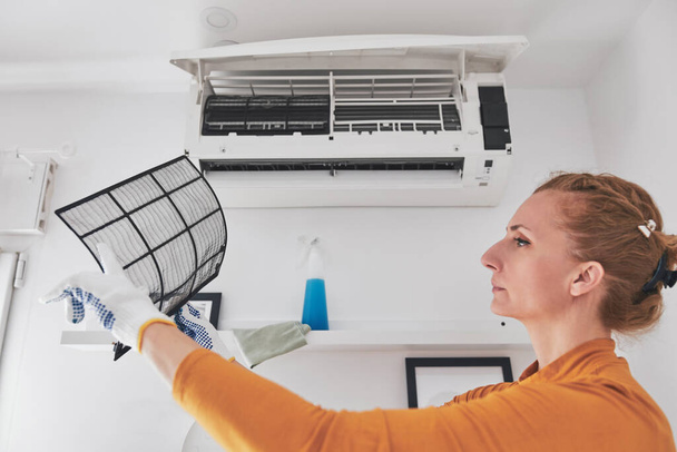 Woman cleaning aircon filters indoor unit at home. - Photo, Image
