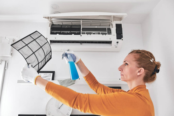 Woman cleaning aircon filters indoor unit at home. - Photo, Image