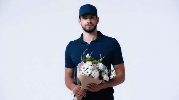 jeune homme de livraison barbu avec bouquet regardant caméra isolée sur blanc - Photo, image
