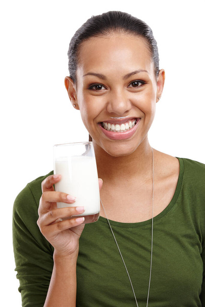 Drink up the nutrition. Portrait of an attractive young woman holding a glass of milk isolated on white - Photo, Image