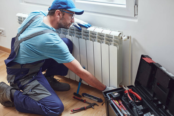 Merkezi ısıtma teknisyeni ve tamirci ev radyatörü, gaz krizi ve mevsimsel sorunları tamir ediyor. - Fotoğraf, Görsel