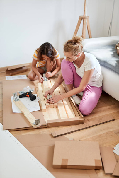 Mutter und Tochter bauen neue Möbel zusammen - Einzug in ein neues Zuhause. - Foto, Bild