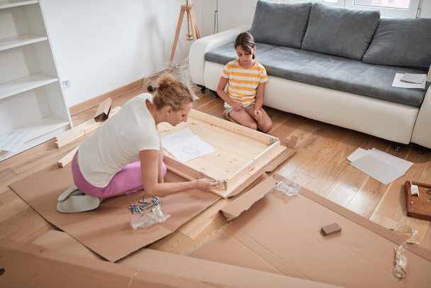 Mère et fille assemblant de nouveaux meubles - emménager dans une nouvelle maison. - Photo, image