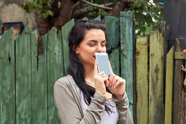 Молодая симпатичная женщина с помощью смартфона на улице. - Фото, изображение