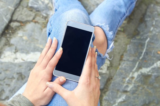Mujer en jeans usando smartphone moderno al aire libre. - Foto, Imagen