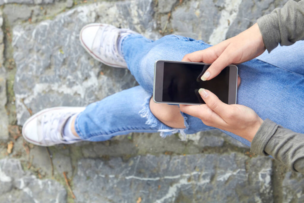 Woman in jeans using modern smartphone outdoors. - Photo, Image