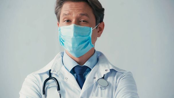 orvos fehér kabátban és orvosi maszk nézi kamera elszigetelt szürke - Fotó, kép