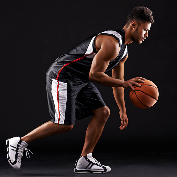 Proezas atléticas. Estúdio tiro de um jogador de basquete contra um fundo preto - Foto, Imagem
