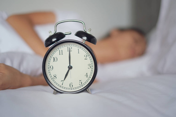 Egy nő alszik az ágyon, kikapcsolja az ébresztőórát, reggel felébred, szelektív fókusz - Fotó, kép