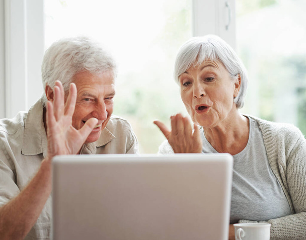Θα τα πούμε με τα εγγόνια. Ένα χαρούμενο ζευγάρι ηλικιωμένων που κάνει βιντεοκλήση σε ένα φορητό υπολογιστή - Φωτογραφία, εικόνα