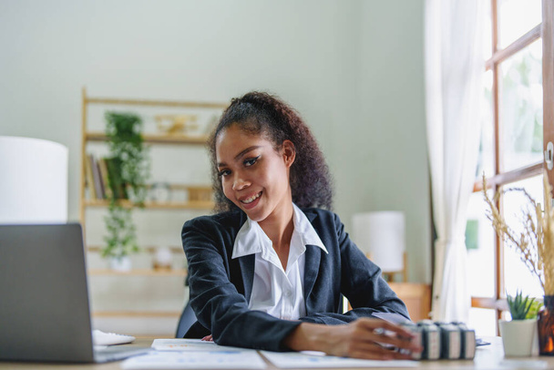 Портрет афро-американской предпринимательницы, которая улыбается, когда работает над увеличением прибыли своего бизнеса - Фото, изображение