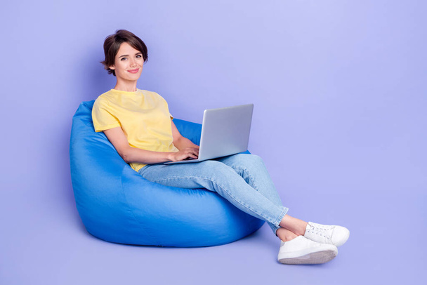 Full length photo of charming person sit comfy bag use wireless netbook isolated on violet color background. - Fotó, kép
