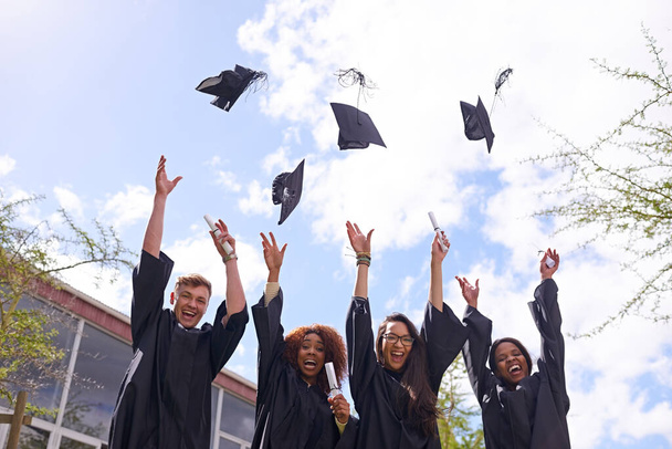 Raison de célébrer. Plan à angle bas de l'élève jetant ses chapeaux de graduation dans les airs - Photo, image