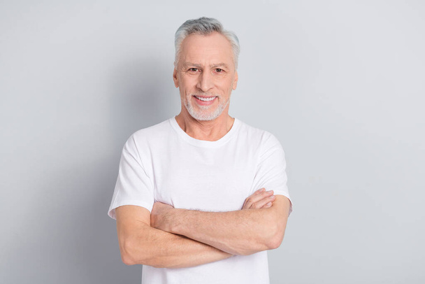 Photo of good older man crossed arms wear white t-shirt isolated on grey color background. - Valokuva, kuva