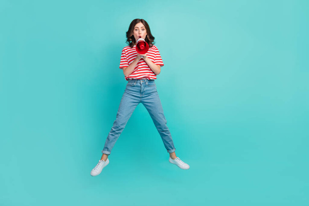 Full length photo of excited pretty girl dressed red t-shirt jumping high telling announcement isolated teal color background. - Фото, зображення