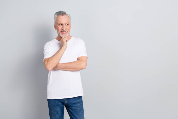 Portrait of creative cheerful man arm chin look interested empty space isolated on grey color background. - Foto, afbeelding