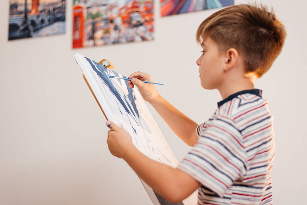 The boy enthusiastically draws a picture by numbers with a brush - Foto, Bild
