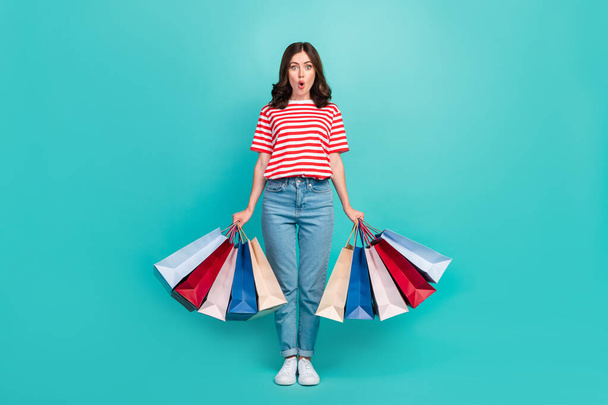 Full length photo of shiny shocked lady wear striped t-shirt walking shopping isolated turquoise color background. - Foto, afbeelding