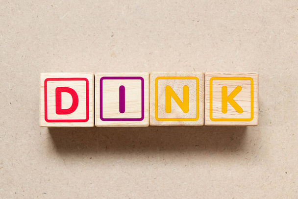 Цвет буквы блока в слове DINK (аббревиатура двойной доход, нет детей или двойной доход, нет детей) на деревянном фоне - Фото, изображение