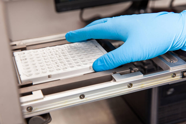 A tudós mintákat tölt be egy RT-PCR termikus ciklusba a laboratóriumban. Valós idejű polimeráz láncreakció technika. RT-PCR technika - Fotó, kép