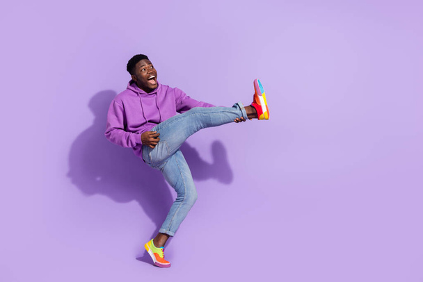 Full body photo of overjoyed positive person hold leg playing guitarist isolated on purple color background. - Foto, afbeelding