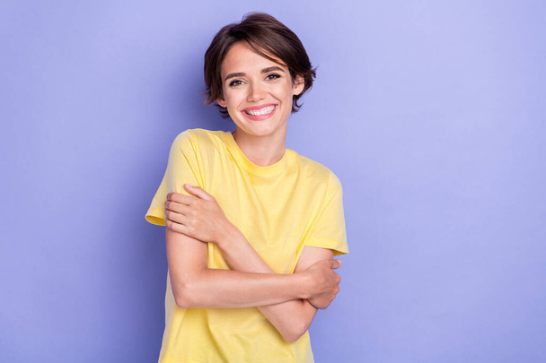 Photo of young gorgeous adorable girl wear bright yellow t-shirt toothy smile hug herself lovely isolated on pastel purple color background. - Φωτογραφία, εικόνα