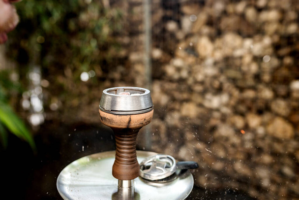 Bir nargile içicisi bir kaseye tütün, bir ısıtıcı ve bir nargile barında hindistan cevizi kömürü üfler. - Fotoğraf, Görsel