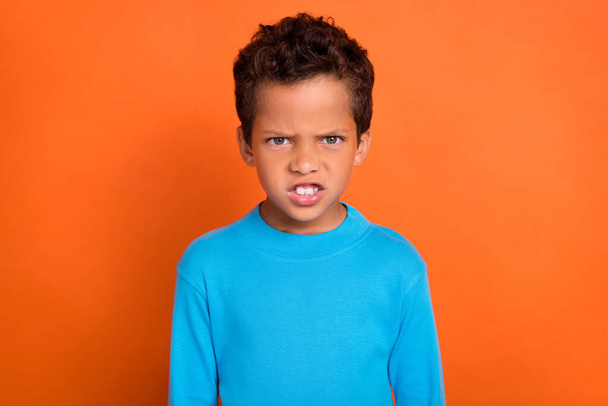 Photo of disappointed dissatisfied boy worried bad situation dressed blue stylish jumper isolated on orange color background. - Foto, Imagem