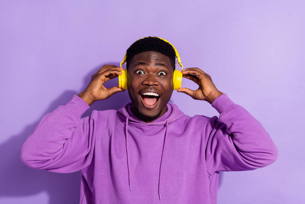 Porträt der erstaunten schönen Person Arme berühren Kopfhörer haben Spaß isoliert auf violettem Hintergrund. - Foto, Bild