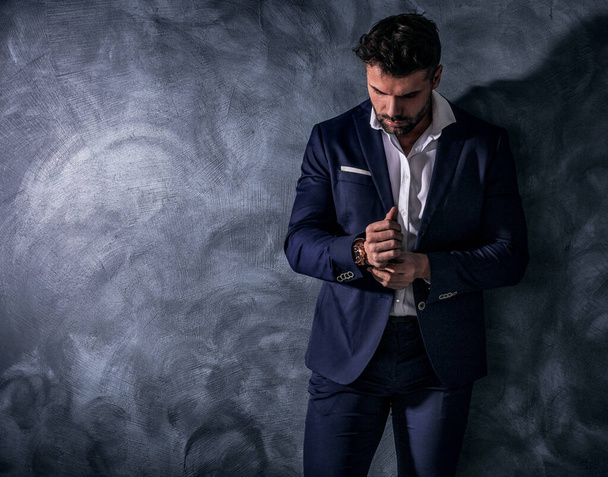 Handsome, confident, elegant man posing in fashionable suit, wearing luxury hand watch. Copy space. Male model. - Fotoğraf, Görsel