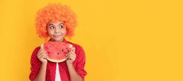 Süslü turuncu peruklu mutlu çocuk taze karpuz dilimi meyve ve organik yiyecek tutuyor. Karpuzlu yaz kızı portresi, yatay poster. Kopyalama alanı olan başlık - Fotoğraf, Görsel