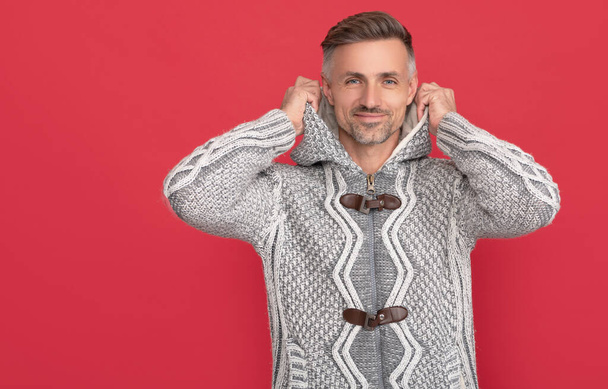 grizzled guy in sweater on red background. hoary man portrait. male fashion model. winter fashion for cold season. mens beauty. hair and skin care. - Photo, Image