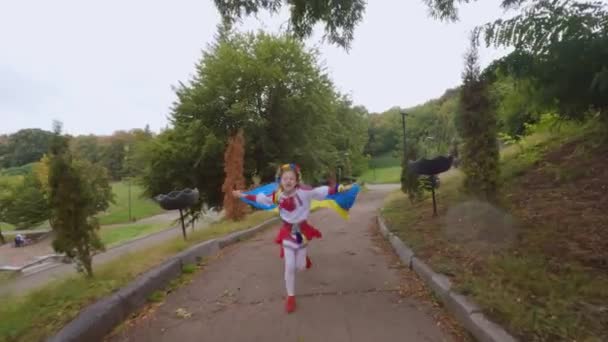 Ragazza ucraina bambino corre con una bandiera in mano. Il bambino si rallegra della bandiera ucraina. - Filmati, video
